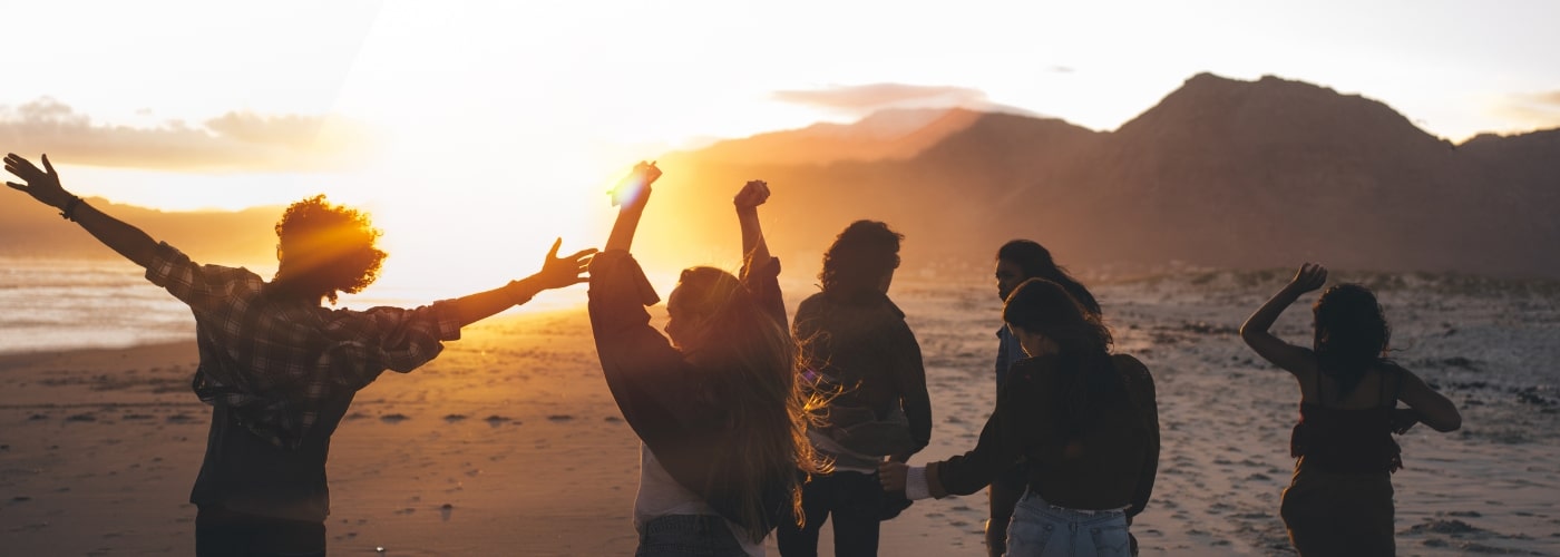 Group of middle aged people dancing on a beach-min